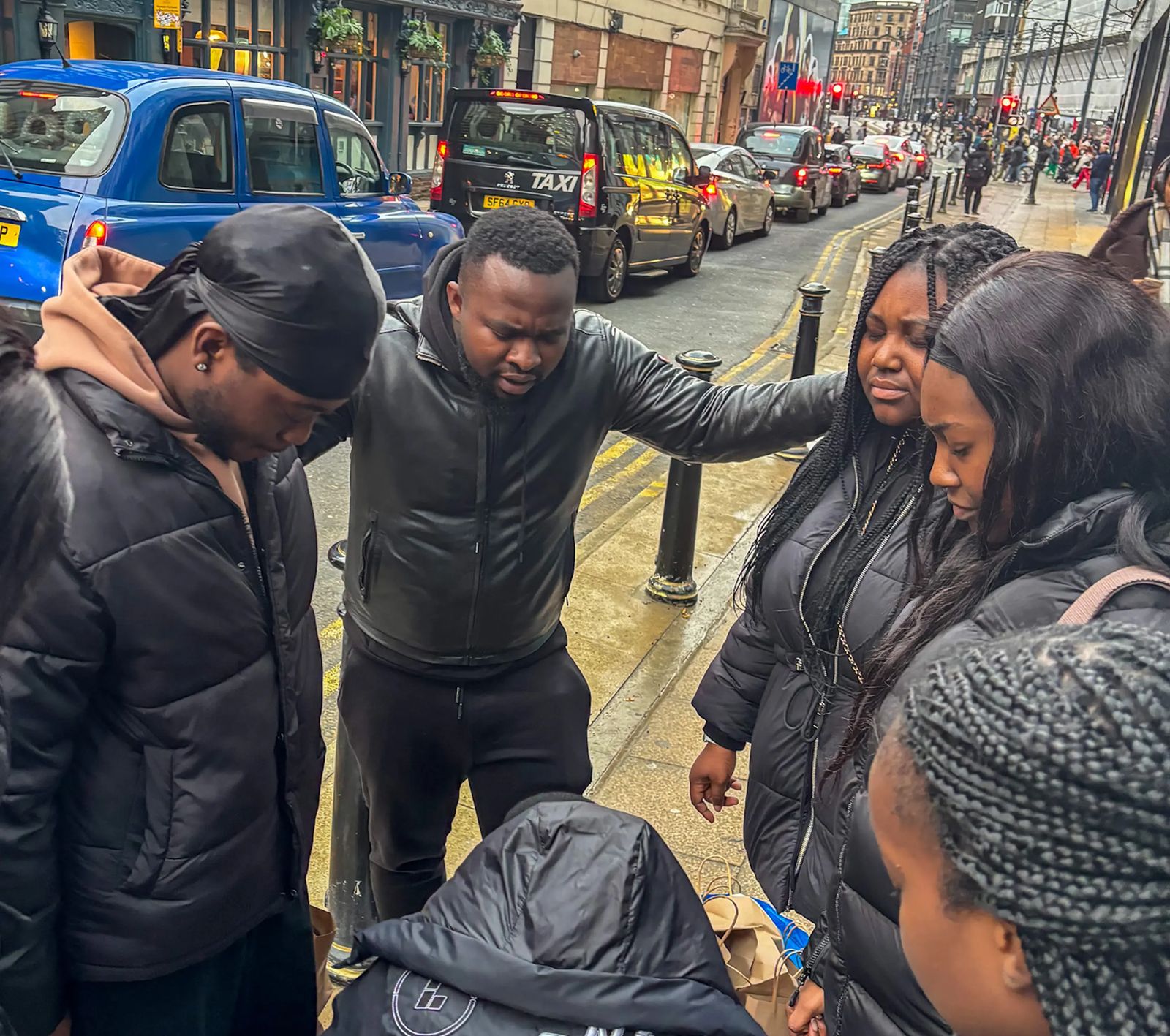 Members of The Kingship Family praying together on a street in Manchester city centre